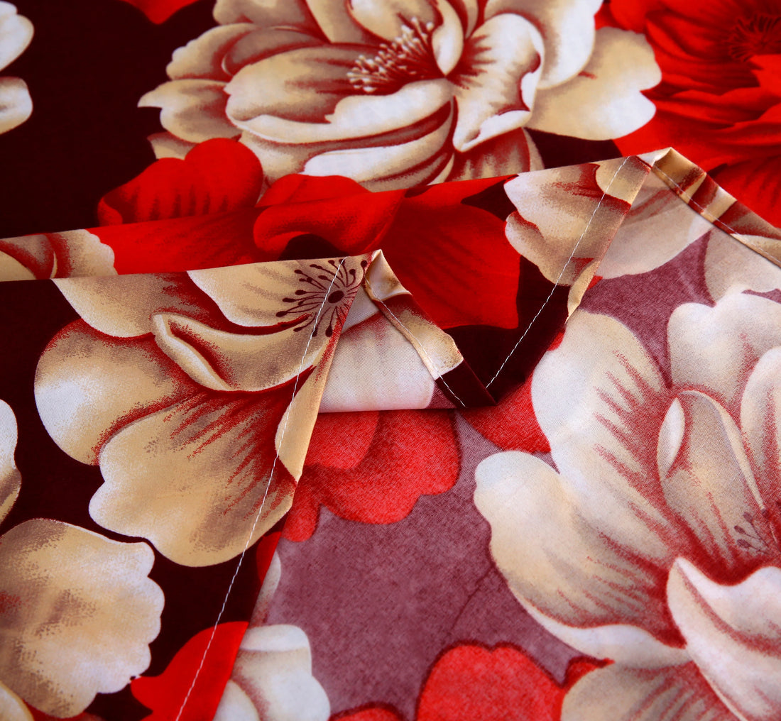 Floral bedding set with red and beige flowers on a bed in a bedroom.