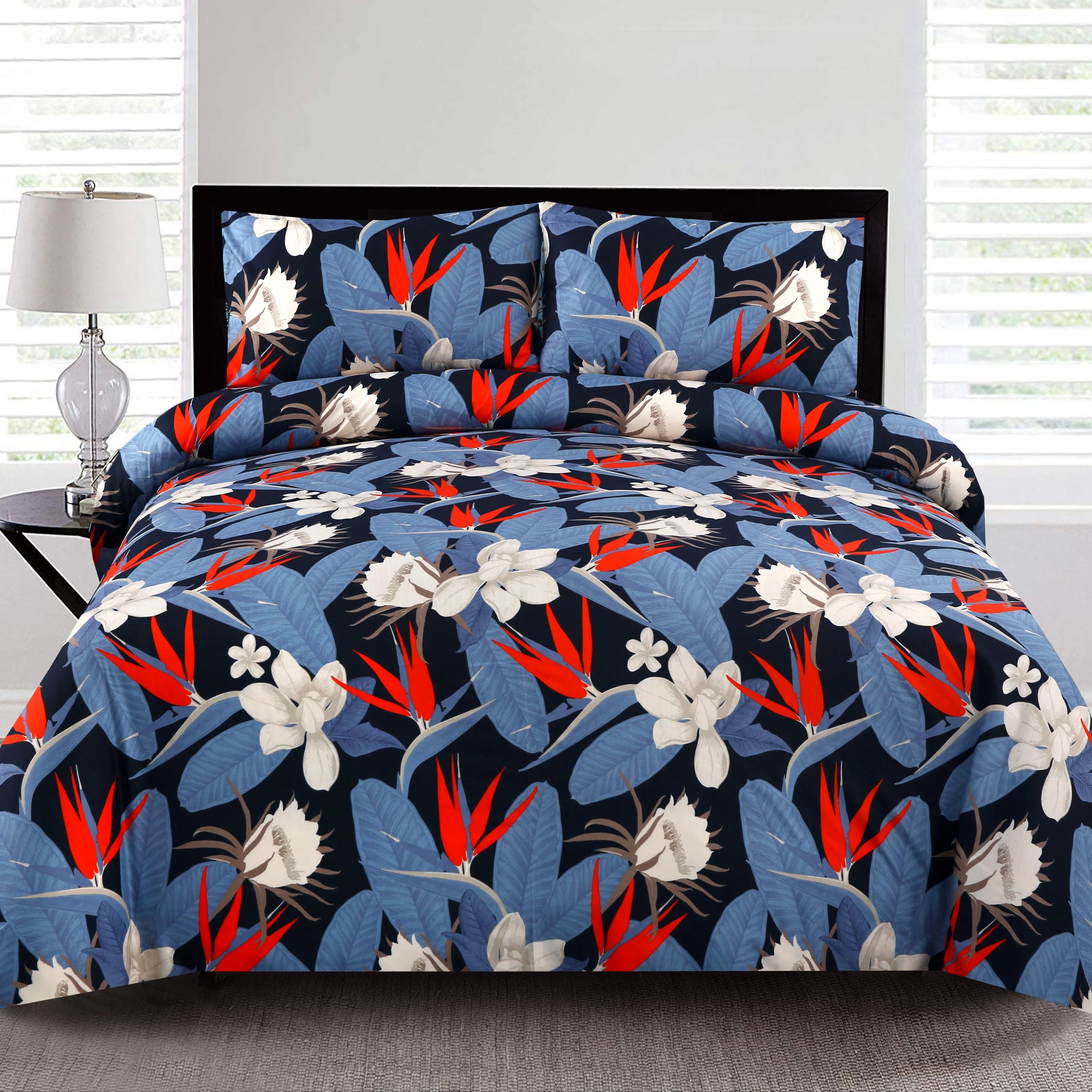 Floral patterned bedding set on a bed with a lamp and window in the background.