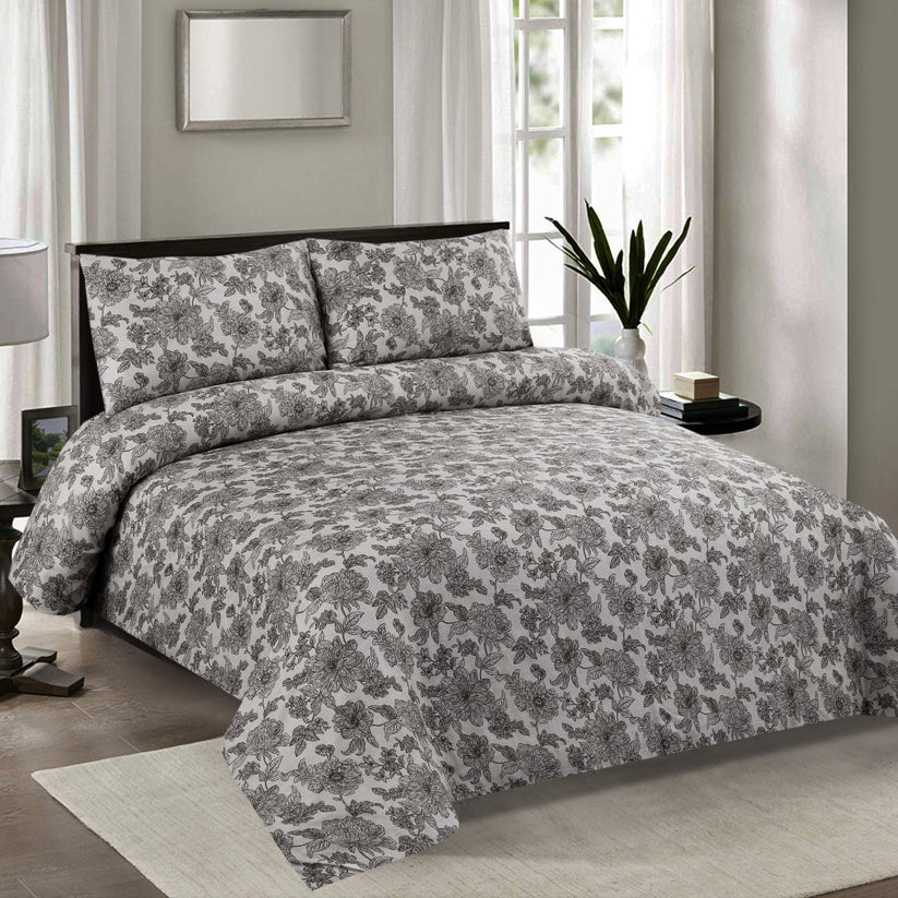 Floral patterned comforter set on a bed in a bedroom with a mirror and window in the background.