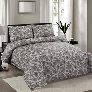 Floral patterned comforter set on a bed in a bedroom with a mirror and window in the background.