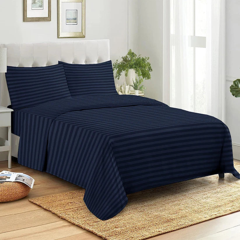 Navy striped bedspread on a bed in a bright bedroom with a plant and framed pictures.