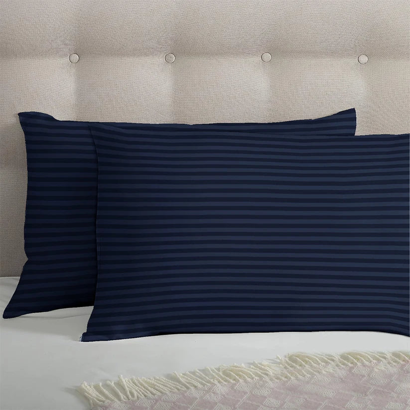 Pair of navy blue striped pillowcases on a bed with a beige headboard.