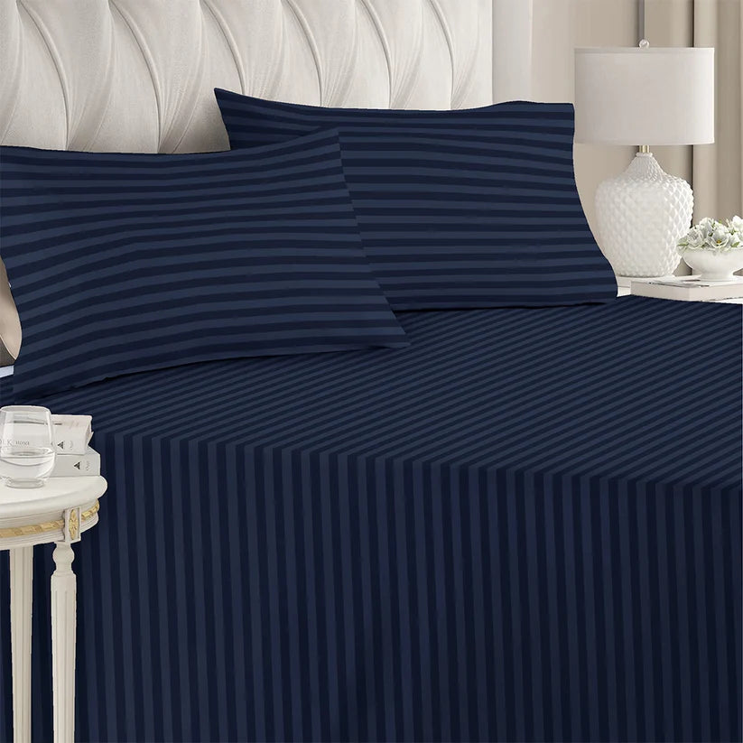 Navy striped bed sheets on a bed with matching pillows, in a bedroom setting.