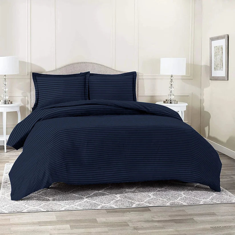 Navy blue striped bedding set on a bed in a bedroom with nightstands and lamps.