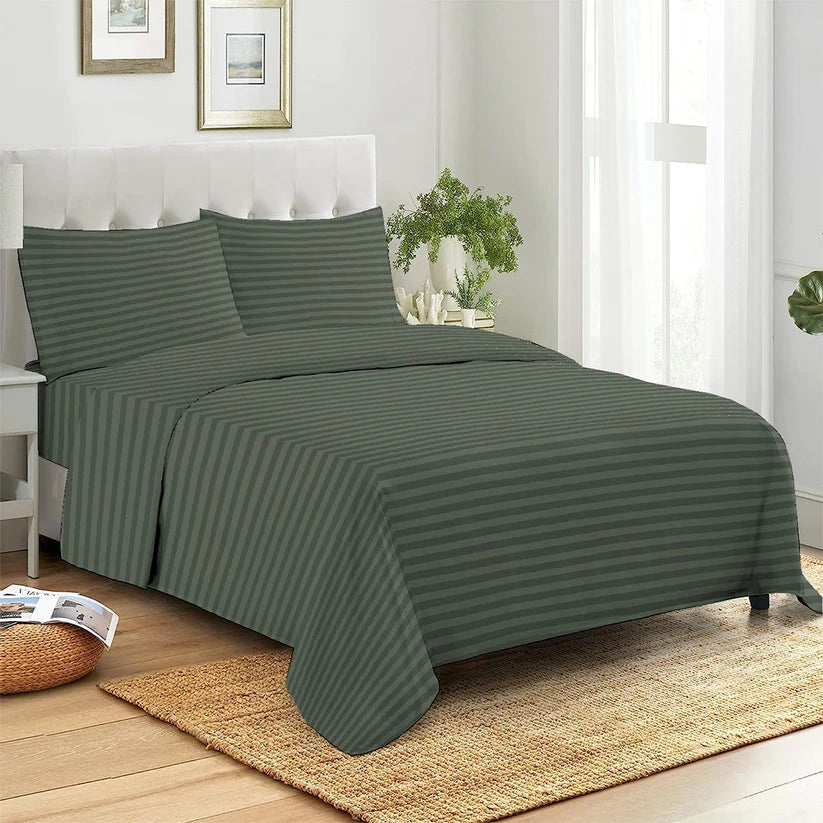 Green striped bedspread set on a bed in a bedroom with a plant and framed pictures.